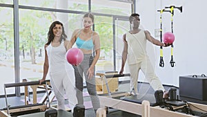 Man and woman exercising with ball at pilates lesson in gym