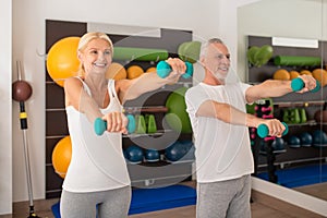 A man and a woman exercising with dumbbells and feeling positive
