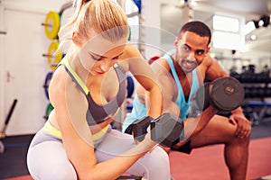 Man and woman exercising with dumbbells at a gym