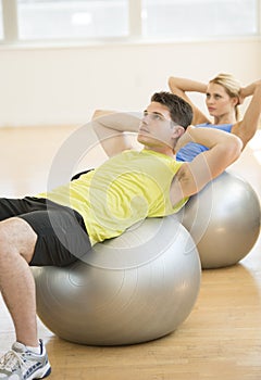 Man And Woman Exercising On Pilates At Health Club