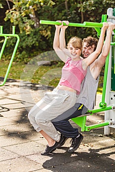 Man and woman exercising on pulldown outdoor.