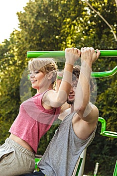 Man and woman exercising on pulldown outdoor.