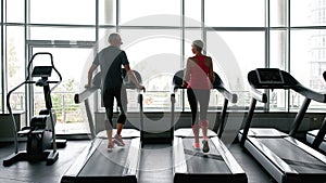 Man and woman exercising together on running machines