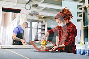 Man and woman in face masks working on glass pane in glazier workshop