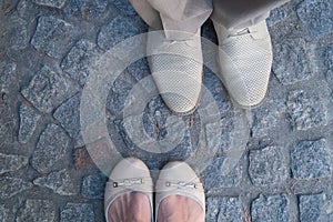 Man and woman face to face stand on cobbles. Focus on the footwear.