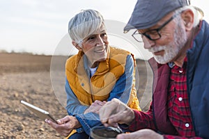 Man and woman farmers checking dirt quality in field