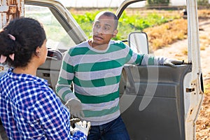 Man and woman farmers signing papers and communicating near car on farmer field