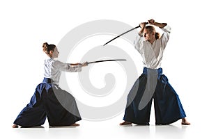 Man and woman fighting and training aikido on white studio background