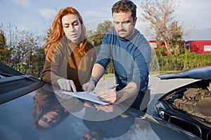 Man and woman filling an insurance car report after car crash