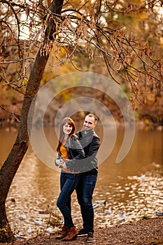 Man and woman flirt in autumn park near river