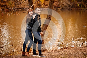 Man and woman flirt in autumn park near river