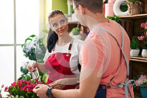 Man and woman florists using diffuser watering plant at flower shop