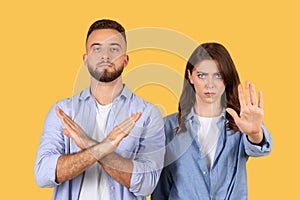 Man and woman gesturing stop, showing denial or refusal on yellow background