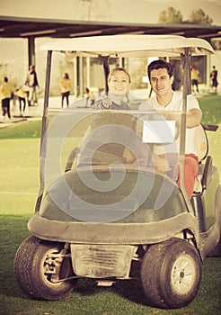 Man and woman golfers riding golf cart