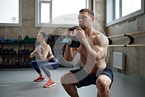 Man and woman with good physique holding heavy kettle bell