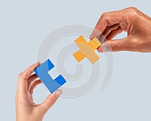 Man and woman hands joining two puzzle pieces. Partnership, connection concept. Mutual understanding, support in