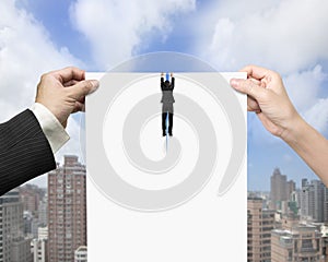 Man and woman hands tearing blank paper with businessman hanging