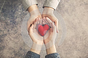 Man and woman hands together with red heart