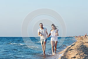 Man and woman happily run along the coastline of the sea.