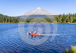 Man and woman in hats ride kayak on the picturesque Trillium Lake overlooking Mount Hood