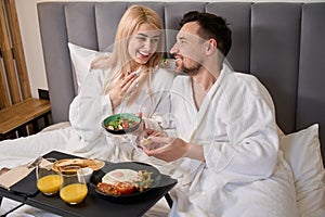 Man and woman are having breakfast together in comfortable hotel room