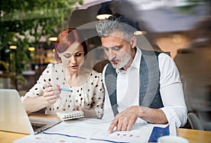 Man and woman having business meeting in a cafe, using smartphone.