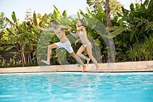 Man and woman having fun jumping in the pool