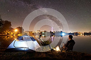 Man and woman having a rest on shore under night sky