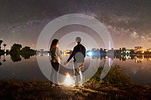 Man and woman having a rest on shore under night sky