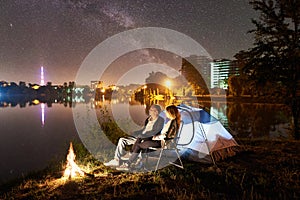 Man and woman having a rest on shore under night sky