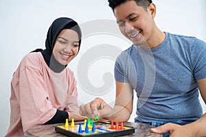 Man and woman in headscarf playing ludo using a board