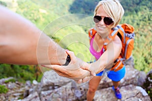 Man and woman helping hand in mountains