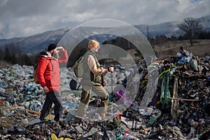 Man and woman hikers on landfill, environmental concept.