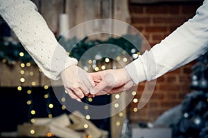 A man and a woman hold hands close-up on the background of blurry lights