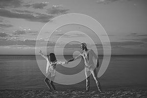 Man and woman hold hands, couple happy on vacation. Couple in love dancing, having fun, sea and skyline background