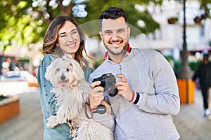 Man and woman holding dog using professional camera at park