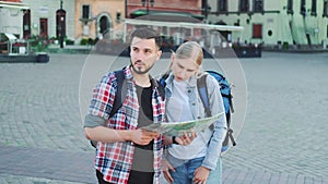 Man and woman holding map and looking for some place on city square