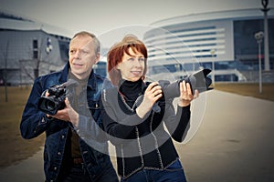 A man and a woman are holding photos and video cameras in their hands