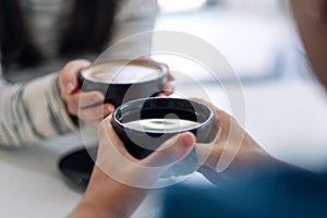 A man and a woman holding two coffee cups together photo