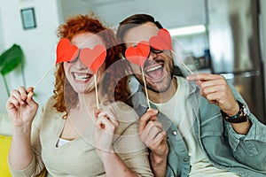 Man and woman at home holding red heart valentine in hands