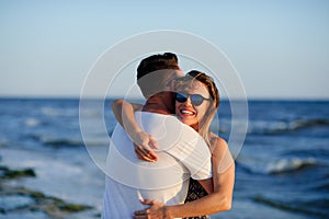 Man and woman hugging in the background of sea and sky.