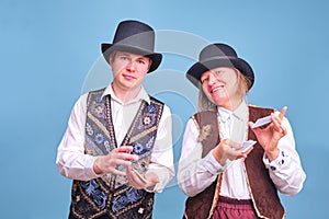 Man and woman illusionists with playing cards on blue background