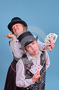 Man and woman illusionists with playing cards on blue background