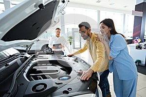 Man and a woman are inspecting a car under hood