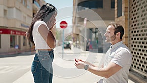 Man and woman interracial couple having engagement proposal at street