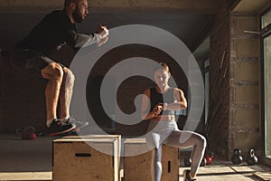 Man and woman jumping tohether on boxes in gym, funcrional workout for people