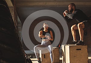 Man and woman jumping tohether on boxes in gym, funcrional workout for people