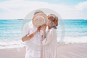 Man and woman kiss on the seashore. Hid behind a hat. To peep. Toned
