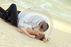 Man and woman kissing on beach in wet clothes