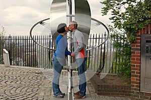 Man and woman kissing being on opposite sides of the Prime Meridian in Greenwich.